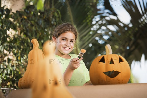 Hispanic girl decorating jack o'lantern