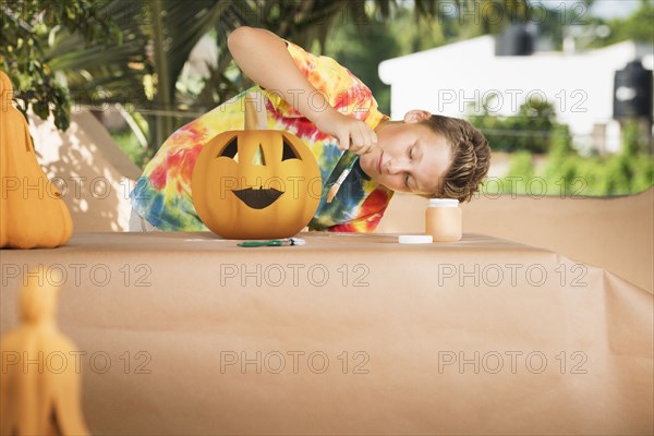 Caucasian boy decorating jack o'lantern