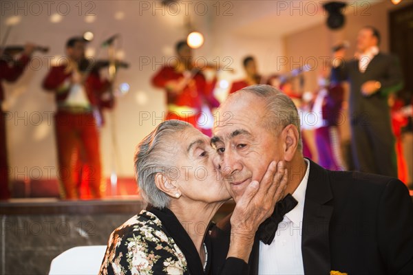 Hispanic couple kissing at wedding reception