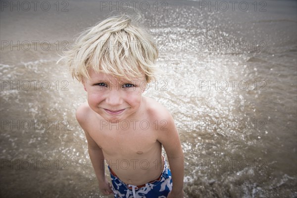 Caucasian boy standing in waves