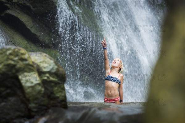 Caucasian girl playing in jungle waterfall