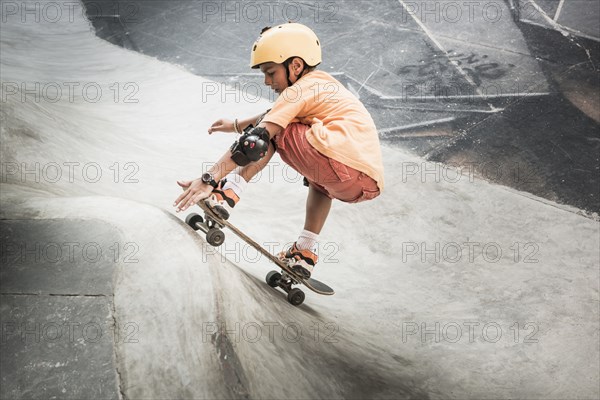 Mixed race boy riding skateboard in skate park
