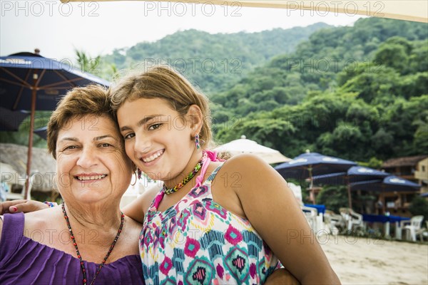 Senior woman and granddaughter smiling on beach