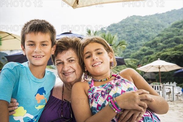 Senior woman and grandchildren smiling on beach