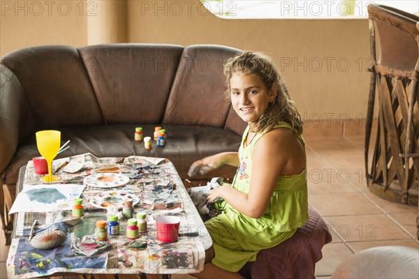 Mixed race girl painting at coffee table