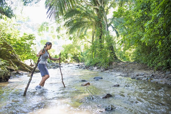 Hispanic woman crossing jungle stream