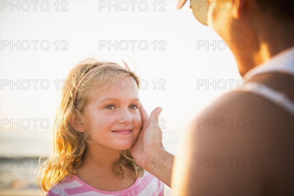 Mother cupping daughter's face on beach