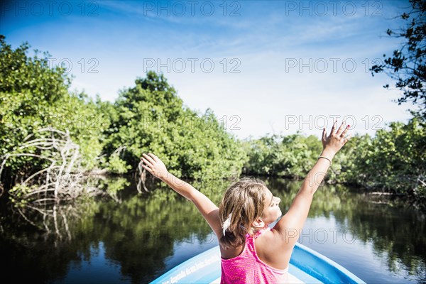 Mixed race girl sitting in canoe in still lake