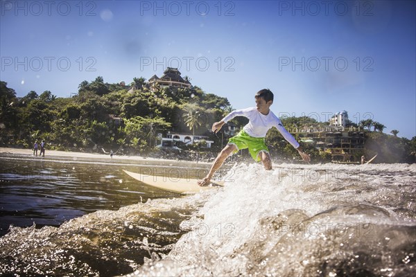 Mixed race boy surfing in ocean