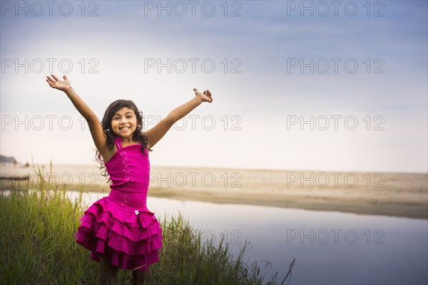 Hispanic girl cheering by still water