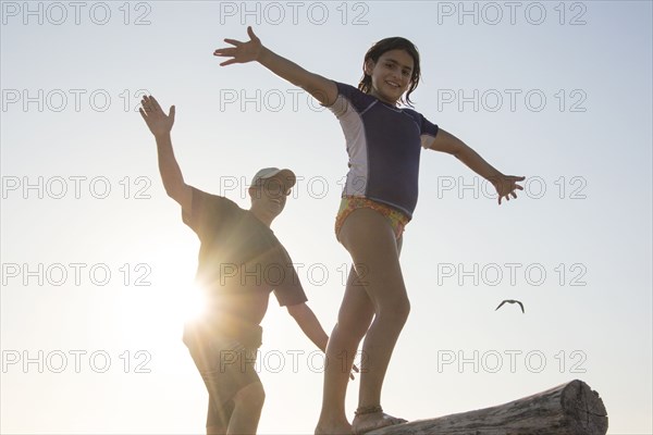 Father and daughter balancing on log