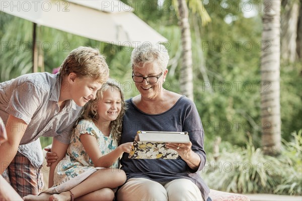 Older Caucasian woman and grandchildren looking at photo album