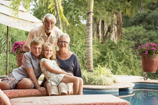 Older Caucasian couple and grandchildren smiling outdoors