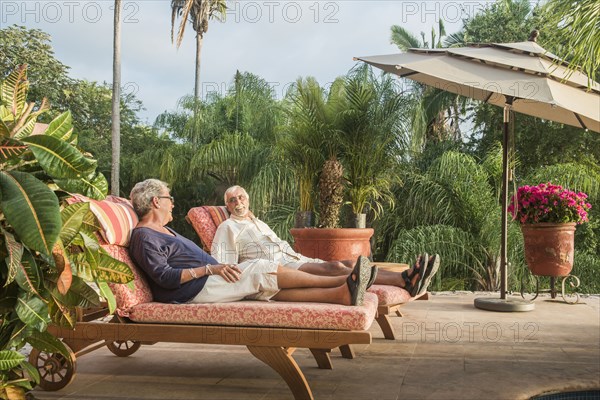 Older Caucasian couple relaxing by pool