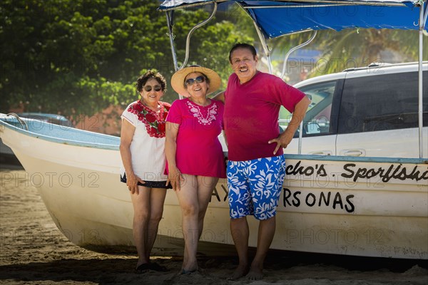 Hispanic friends smiling by boat on beach