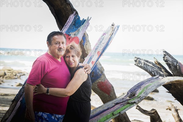 Hispanic couple hugging on beach