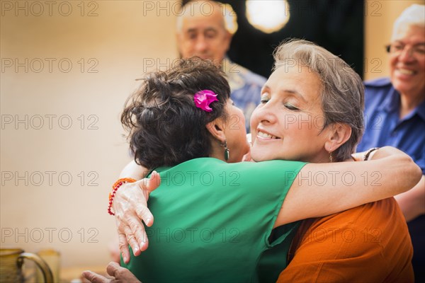 Hispanic women hugging in restaurant