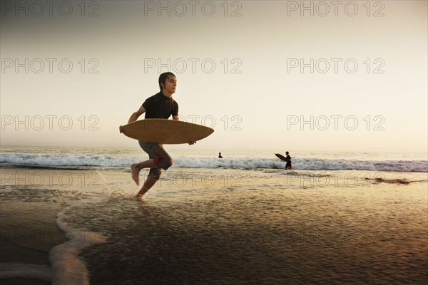 Caucasian boy skimboarding at beach