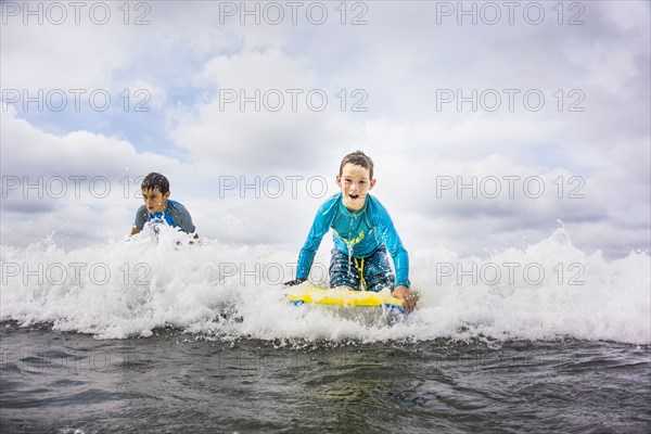 Boys surfing together in waves