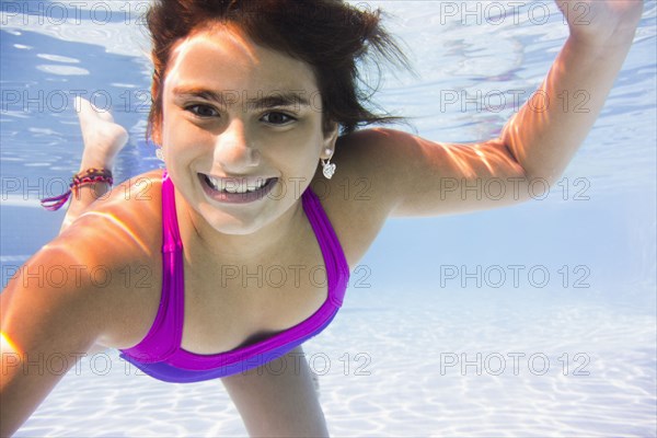 Mixed race girl swimming underwater