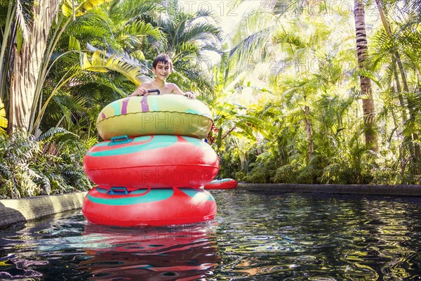 Mixed race boy playing in stacked inner tubes in pool