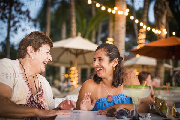 Mother and daughter laughing at outdoor table