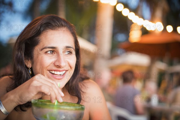 Hispanic woman drinking cocktail outdoors