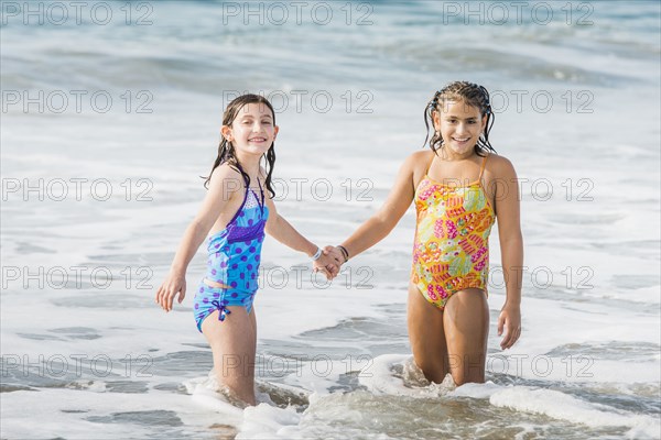 Girls holding hands in ocean waves