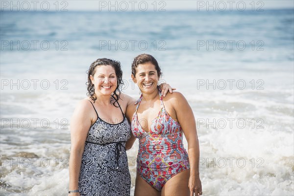 Women smiling together in ocean waves