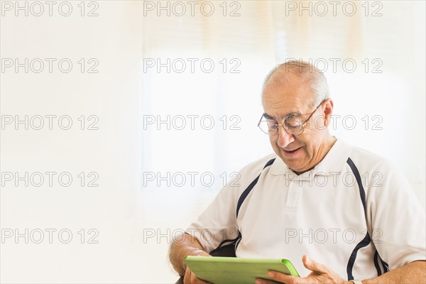 Older Hispanic man using digital tablet