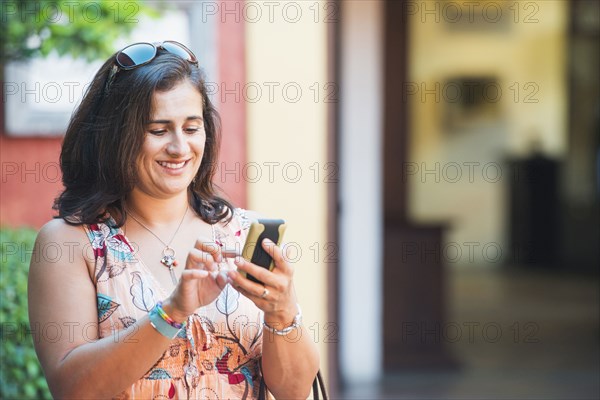 Hispanic woman using cell phone in city