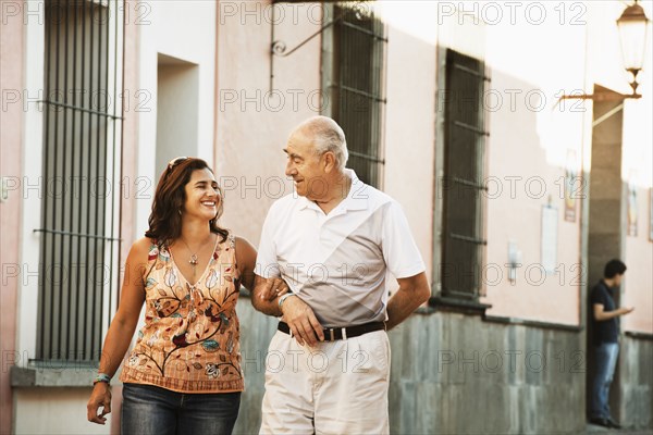 Hispanic father and daughter walking together in city