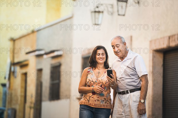 Hispanic father and daughter using cell phone in city