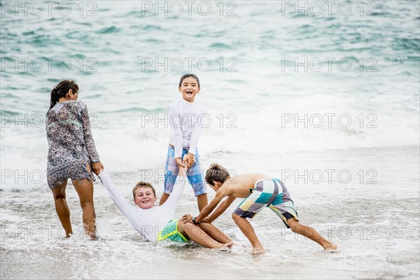 Family playing together in waves on beach