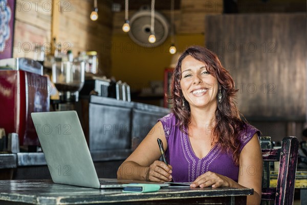 Hispanic woman using laptop in coffee shop