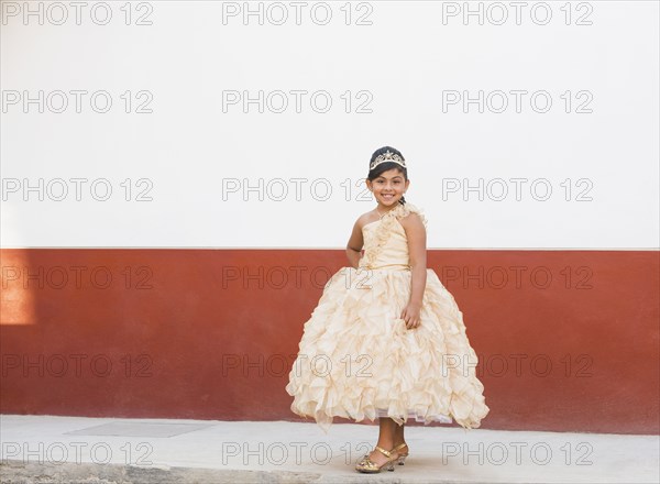 Hispanic girl posing in ornate gown and tiara