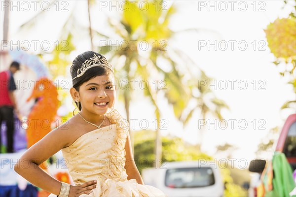 Hispanic girl posing in ornate dress and tiara