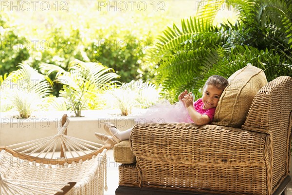 Hispanic girl sitting in armchair outdoors