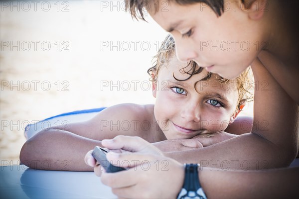 Boys playing with cell phone together outdoors