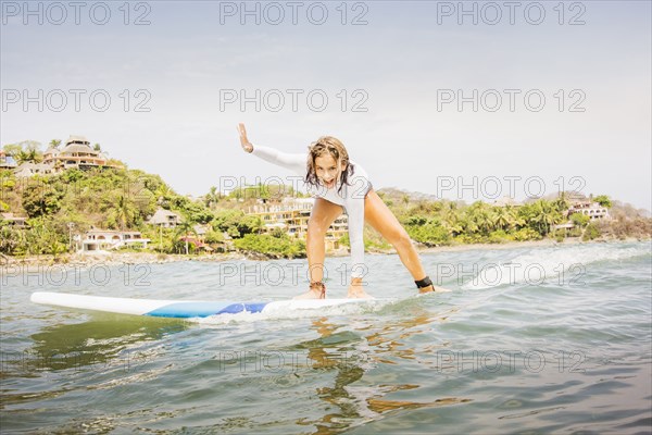 Mixed race girl surfing in waves