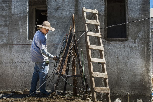 Hispanic worker with wires at construction site