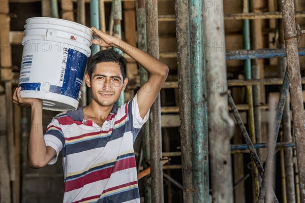 Hispanic construction worker carrying bucket at construction site