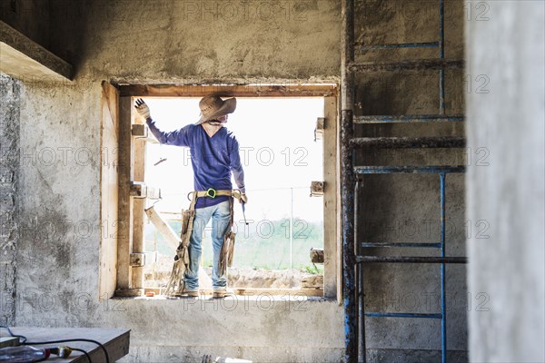 Hispanic construction worker in window at construction site