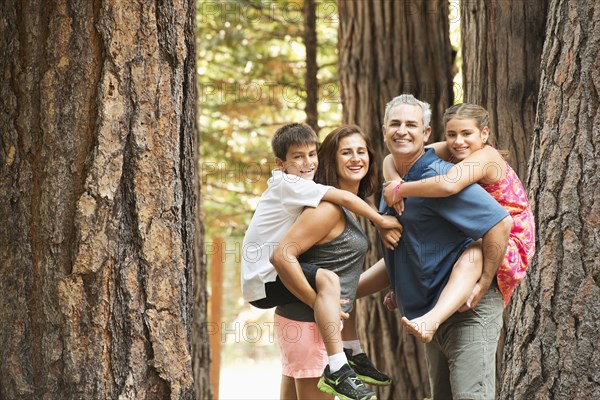 Parents carrying children piggyback in forest