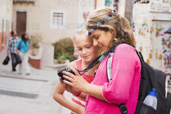 Girls looking at digital camera photographs on vacation