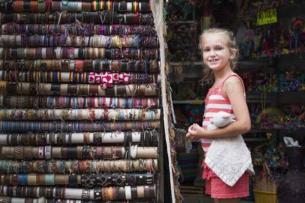 Caucasian girl admiring woven bracelets for sale in market