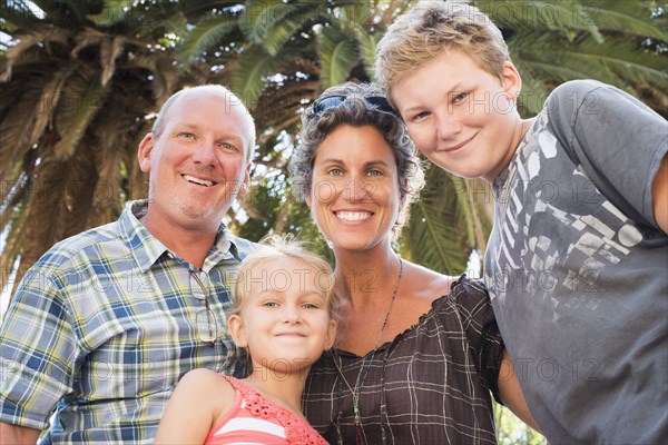 Caucasian family smiling under palm tree