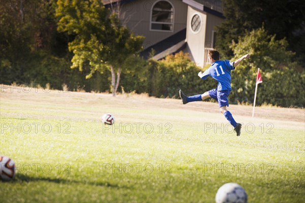 Mixed race boy playing soccer on field