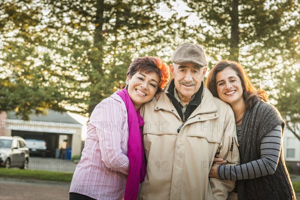 Hispanic parents and daughter smiling outdoors