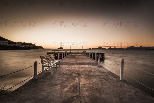 Stone walkway and ocean waves under sunset sky